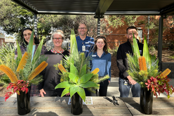 Steven Wells, Garden and Grounds, standing with Austin Health Allied Health team members with beautiful vases of flowers and foliage